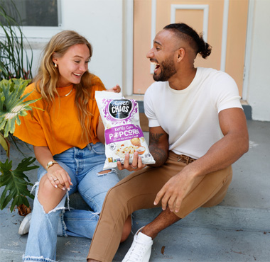 couple sitting on patio enjoying a bag of Sweet Chaos Kettle Corn Popcorn